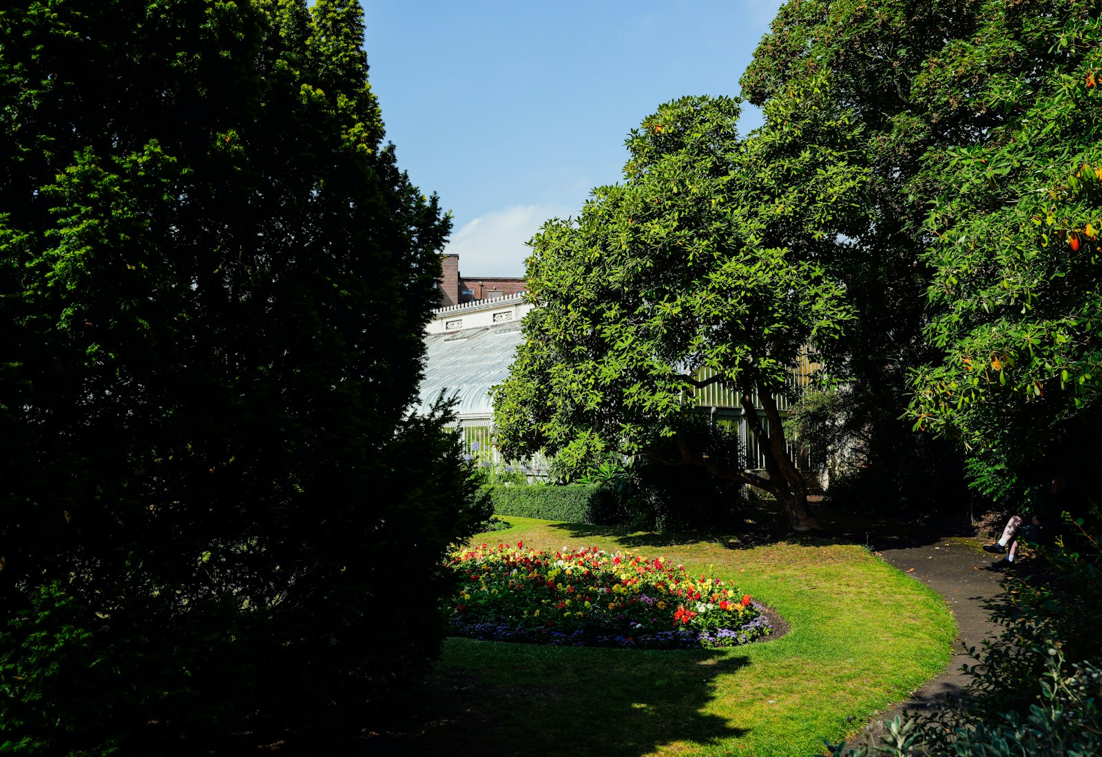 Garden path with lawn, trees, and colorful flower beds. Example photograph.